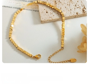 Detailed macro view of gold square bead bracelet with K18 engraved tag and lobster clasp