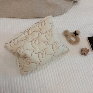 Detail of quilted white cosmetic bag with red rabbit embroidery and logo tag