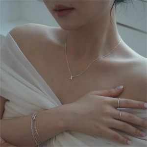 Close-up of elegant silver X-shaped pendant necklace and matching minimalist jewelry set