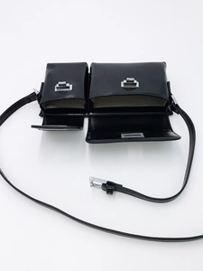Detailed view of dual-compartment black leather baguette bag with silver buckles
