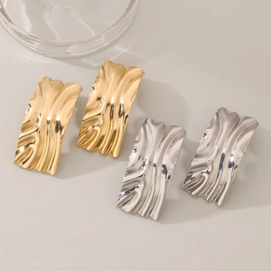 Detail of rectangular wavy metal earrings in polished gold and silver finishes