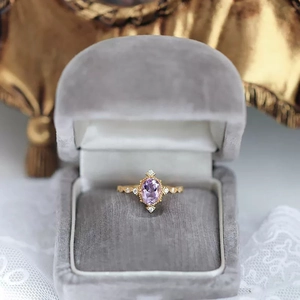 Macro view of vintage gold ring with oval amethyst and white diamonds in jewelry box