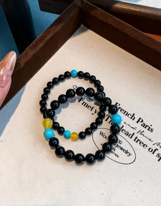 Close-up of aquamarine agate beaded bracelets with black obsidian stones on vintage canvas