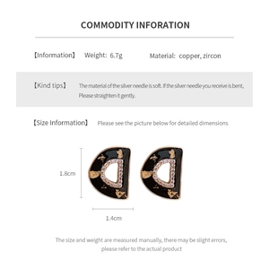 Detail view of vintage black and gold letter D stud earrings with zircon and silver pins