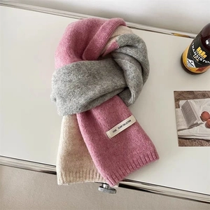 Détail d'une écharpe en maille tricolore rose et beige avec une étiquette cousue