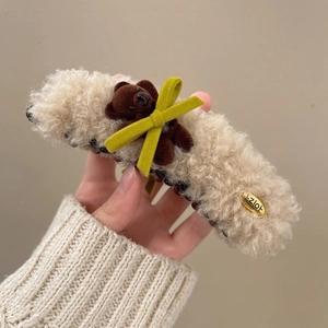 Detail of plush beige hair claw clip with a 3D brown bear and soft lamb wool texture