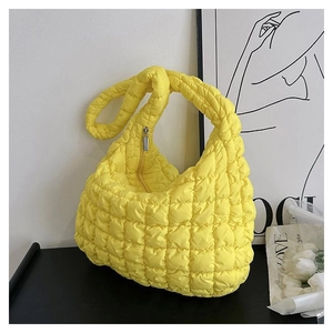 Close-up of bright yellow quilted bubble bag texture and silver metal zipper detail