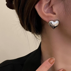 Polished silver heart stud earring in 3D puff design on model for vintage minimalist look