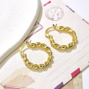 Elegant gold twisted rope hoop earrings displayed on a vintage aesthetic background