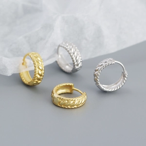 Close-up detail of s925 silver braided twist huggie hoop earrings in gold and silver