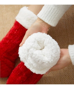 Detail of red knit socks featuring thick white faux fur lining and plush cuffs for warmth