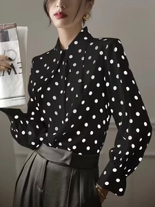 Detailed view of women's black polka dot shirt with lapel collar and lantern sleeves
