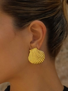 Close-up of elegant gold shell earring with textured finish worn by a model