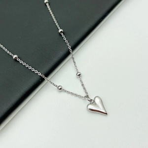 Detail shot of a polished silver heart pendant on a beaded cable chain necklace