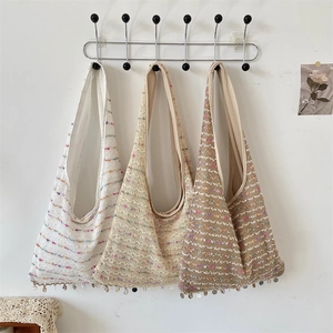 Three colorful knitted tote bags with sequins hanging on a black metal coat rack