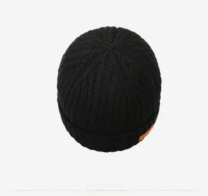 Detailed top view of black knit beanie featuring thick texture and orange leather side tag