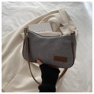 Detail of grey tweed fabric and brown leather shoulder strap on retro women's handbag