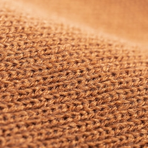 Close-up macro of brown knitted fabric showing premium fiber texture and warm knit pattern
