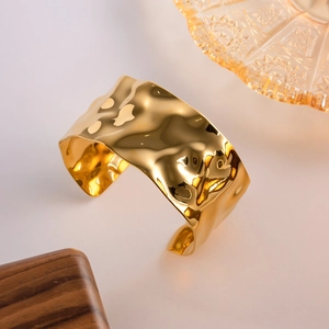 Macro shot of 18K gold hammered metal texture on wide irregular open cuff bracelet