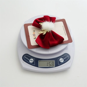 Detailed shot of Christmas red velvet bow hair clip with antlers on a digital scale
