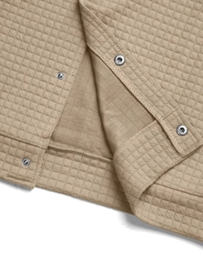 Macro detail of beige quilted diamond pattern fabric with metallic snap button closure