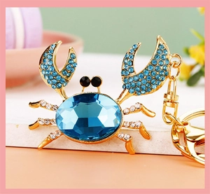 Macro shot of crab keychain with blue faceted rhinestone and gold metal details
