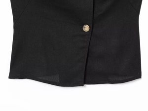 Detail of black linen blend fabric texture and single button closure on a vest top