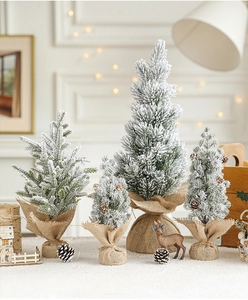 Mini tabletop flocked Christmas trees with snow effect and burlap base in cozy home setting