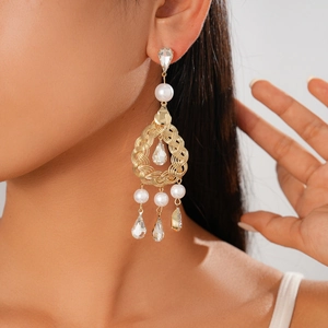 Close-up of model wearing teardrop drop earrings with rhinestones and faux pearls