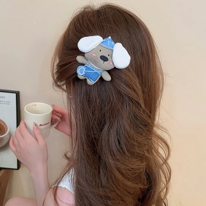 Detail of plush puppy hair clip with blue overalls styled on brunette curly hair