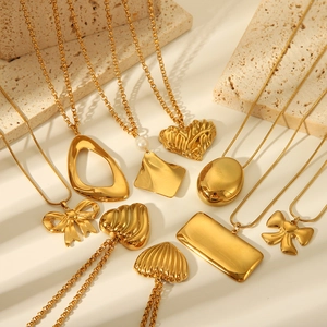 Detailed flat lay of golden heart and butterfly pendants on textured stones