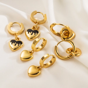Golden heart charm hoop earrings set with black enamel details on white silk
