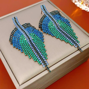 Macro shot of leaf-shaped earrings with blue and green rhinestones on jewelry box