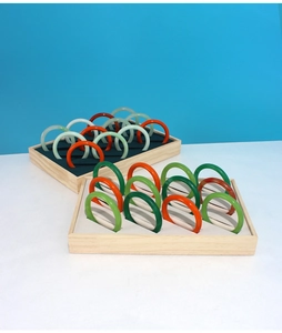 Top view of multi-colored round jade bracelets arranged on natural wooden display trays