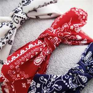 Women's paisley knot headbands in white, red, and navy blue fabric on soft fur background