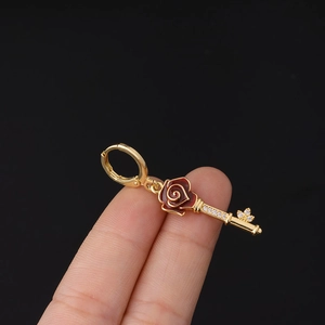 Detailed view of a gold-plated key earring featuring a red rose and sparkling zircons