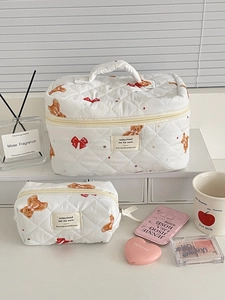 Close-up of quilted cosmetic bags with cute teddy bear and red ribbon pattern print