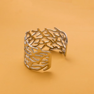 Detail of a silver open cuff bracelet with intricate hollow-out geometric patterns