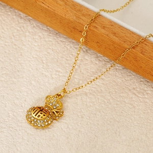 Détail macro du collier pendentif sac porte-bonheur doré avec strass blancs et signe Fu