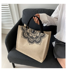Close-up of linen tote bag with black mandala print and button closure on grey sofa