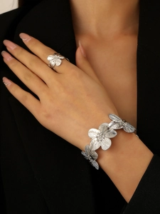 Detail of silver textured flower bracelet and ring worn on model with black suit