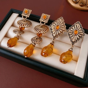 Vintage gold drop earrings with amber resin stones in a luxury black jewelry box