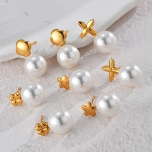 Elegant gold pearl stud earrings set with clover and star shapes on a stone background
