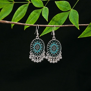 Macro detail of tribal silver earrings with teal floral enamel and silver tassels