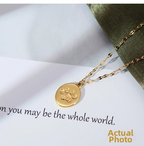 Detailed macro shot of gold oval pendant featuring delicate cat paw print engraving