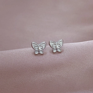 Polished silver butterfly stud earrings in titanium steel on soft purple silk fabric