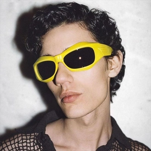 Close-up of a male model wearing yellow sporty wrap-around Y2K sunglasses with dark lenses