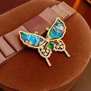 Macro detail of gold-plated butterfly brooch with abalone shell and zircon wings