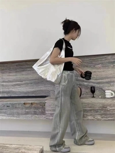 Détail d'un grand sac cabas argenté métallisé au design minimaliste porté à l'épaule