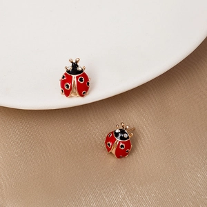 Détail macro de boucles d'oreilles coccinelle avec émail rouge et cristaux blancs